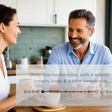 Man and woman sitting together in a kitchen, smiling at each other.