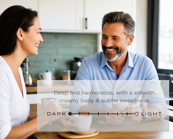 Man and woman sitting together in a kitchen, smiling at each other.