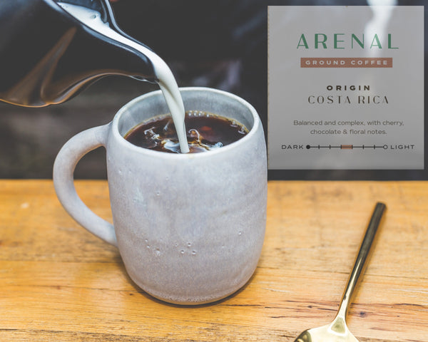 Coffee being poured into a mug with Arenal Costa Rica coffee packaging in the background.